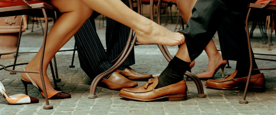 Couples at cafe table, woman's foot touching man's ankle, low section